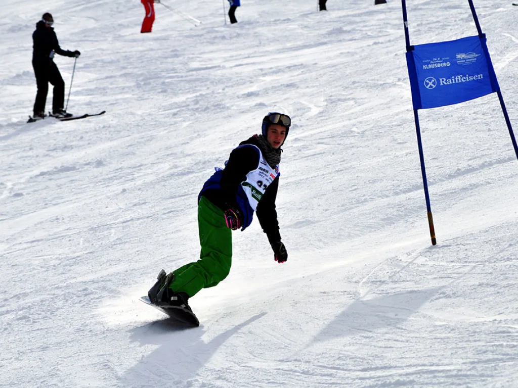 Snowboarder in grüner Hose zieht eine Kurve.